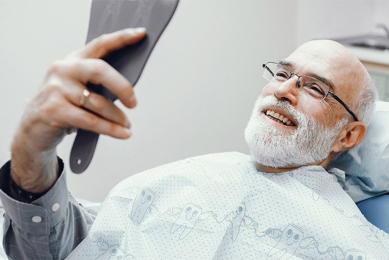 Very nice guy in dental chair at bonvallet dental smiling looking into mirror happy with his new full mouth reconstruction